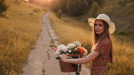 Lens-flare:-smiling-happy-woman-in-short-dress-is-riding-a-bicycle-with-a-basket-and-flowers-in-the-park-with-green-trees-around-during-the-dawn.-Slowmotion-shot